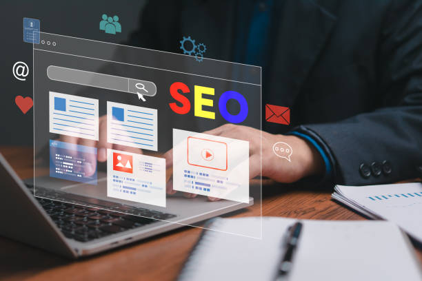 A man is typing on a laptop with a screen displaying a website with the words SEO on it